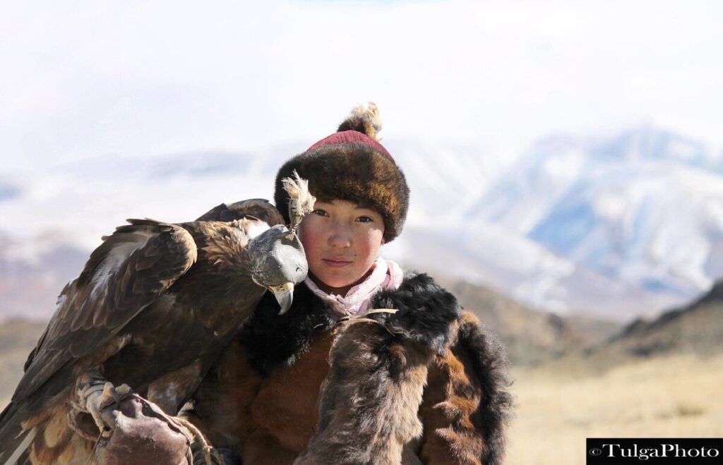 Eagle Huntress with her eagle perched on her arm closeup
